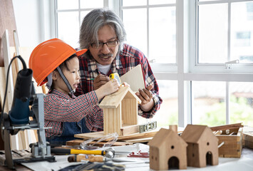 Asian little girl learning and playing with grandfather in wooden shop concept for enhancing the...