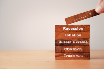 Hand stacking wooden block which print screen scenario since trade war COVID-19 Russia Ukraine...