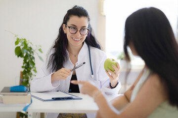 Smiling female doctor nutritionist giving consultation about diet plan and healthy eating to the...