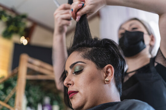 Horizontal image of a Latina woman in the beauty salon having her hair cut.