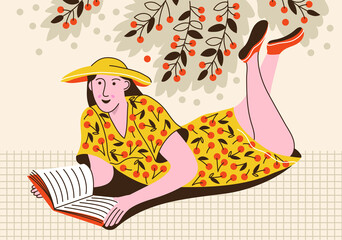 Pretty woman lying down on grass under cherry tree and reading a book. Female student on vacation. Summer time