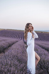 beautiful woman with blond hair in elegant dress and accessories posing in blooming lavender field