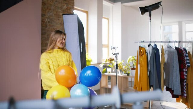 Fashion studio shooting of a happy young woman with balloons , backstage of photoshooting .