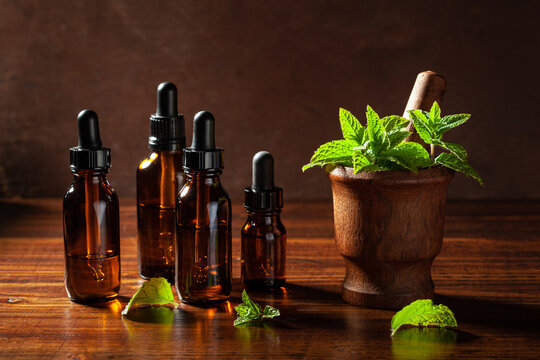 fresh mint Peppermint herb leaves in mortar and essential oil in dropper bottles