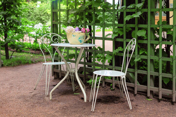 Fototapeta na wymiar Sunny outdoor cafe with wrought iron white furniture