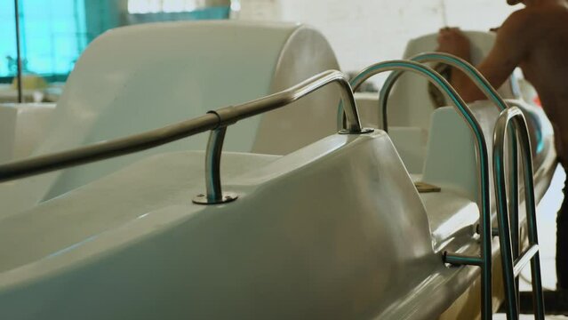 A man pushes a fiberglass plastic boat with a rag. Small-scale production of boats in a private workshop