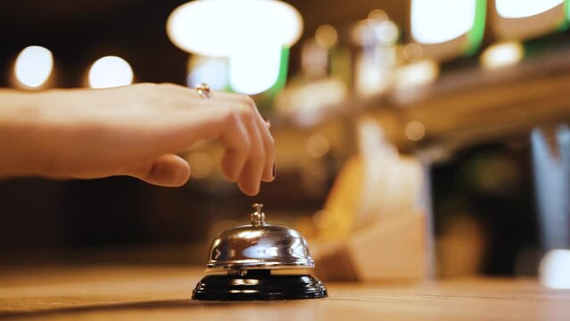 Women's hand touching restaurant ring bell, slow motion