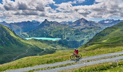nice active senior woman riding her electric mountain bike in the silvretta mountain range above...