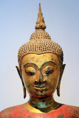 The head of an ancient Buddha statue was made of gold. image on copy space white-blue background.