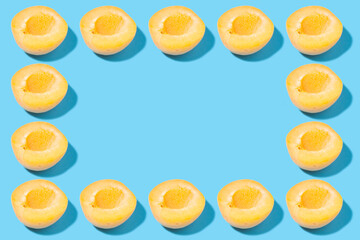 Naklejka na ściany i meble Creative frame of halves of yellow apricots on a blue background - mockup for advertising