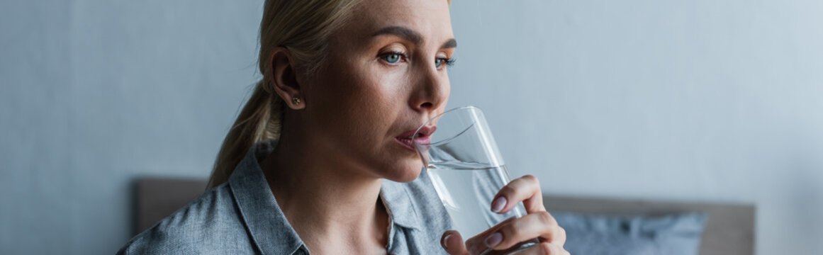 blonde woman with menopause drinking fresh water from glass, banner.