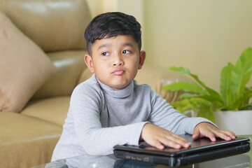 The Asian boy focusing working on laptop and have a cute smile