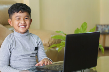 The Asian boy focusing working on laptop and have a cute smile