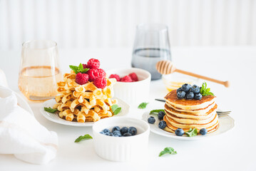 Summer breakfast. Homemade baked ricotta pancakes and Belgian waffles with fresh berries on white wooden table