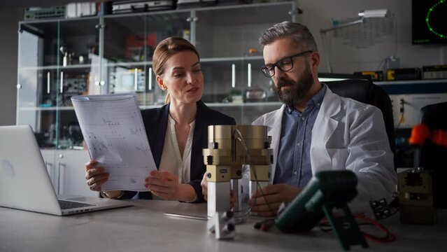 Robotics engineers working on laptop and desinging modern robotic arm in laboratory.