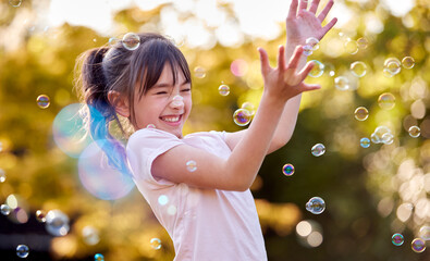Smiling Girl Outdoors Having Fun Playing With Bubbles In Garden