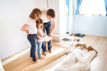 Dad,little girls daughters assemblle wooden baby bed according to instructions in kids room....