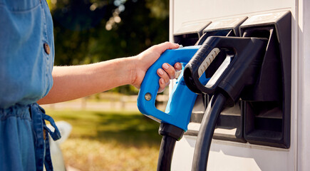 Close Up Of Hand Using Charging Station To Recharge Zero Emission Electric Car
