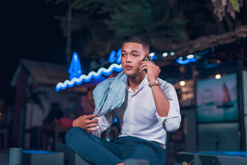 Candid shot of a handsome and dapper young man hanging out at an outdoor bar. Holding a phone...