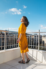 Obraz premium a smiling woman stands on a roof overlooking the city and the wind inflates her dress