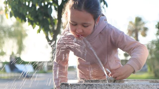 A cute child girl is drinking from water fountain at the park, close-up 4k footage