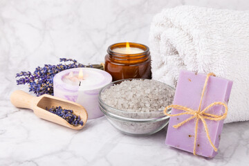 Obraz na płótnie Canvas Lavender spa.Sea salt, lavender flowers, aroma candle, body cream and handmade soap.Natural herbal cosmetics with lavender flowers on marble background.Relax concept.Beauty treatments.Copy space. 