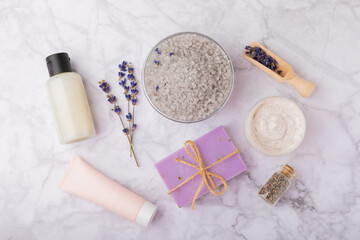 Fototapeta na wymiar Lavender spa. Sea salt, lavender flowers, body cream and handmade soap. Natural herbal cosmetics with lavender flowers on marble background. Relax concept. Beauty treatments. Copy space.