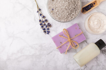 Fototapeta na wymiar Lavender spa. Sea salt, lavender flowers, body cream and handmade soap. Natural herbal cosmetics with lavender flowers on marble background. Relax concept. Beauty treatments. Copy space.