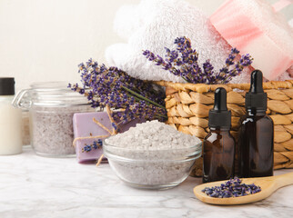 Obraz na płótnie Canvas Lavender spa.Essential oils,sea salt,body scrub,lavender flowers and handmade soap.Natural herbal cosmetics with lavender flowers on marble background.Relax concept.Beauty treatments.Copy space.