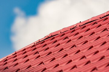 Perspective shot to a modern roof red tiles against a cloudy sky