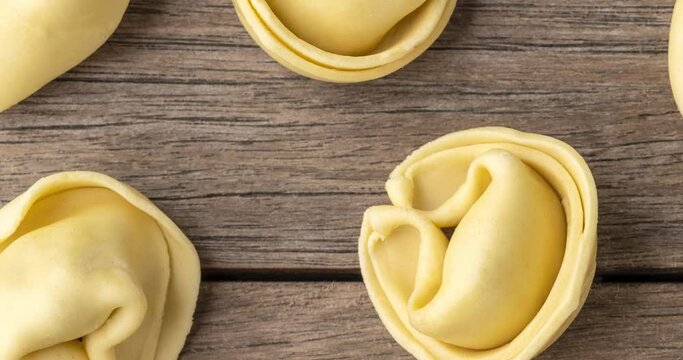 Uncooked cappelletti or tortellini over wooden table