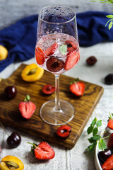 Sparlking wine with berries. Refreshing cooling sparkling summer drink with fresh strawberry, cherry and ice cubes. Iced prosecco champagne with ice cubes and berries