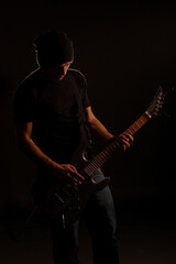 Obraz premium man playing on electric guitar in the dark