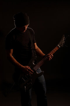 man playing on electric guitar in the dark