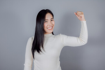 Asian woman in raise hands glad excited cheerful on gray background