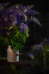 A bouquet of lupines in a jar. A farmhouse.Wildflowers. Vertical photo on a dark background.