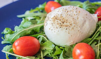 Caprese salad. Healthy meal with tomatoes, mozzarella, spices and fresh rocket. Home made, tasty food. Concept for a tasty and healthy vegetarian meal.