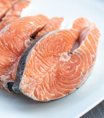 Close up of three fresh salmon slices, in a white plate, on a slate table..Tasty food from Italian cuisine and from the Mediterranean sea. Concept for a tasty and healthy meal.