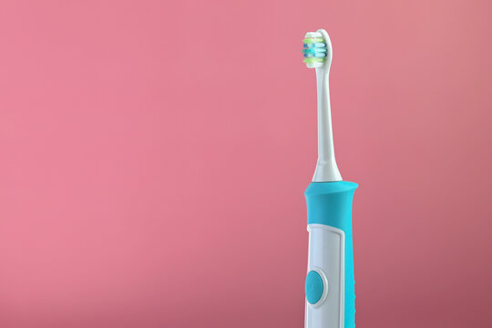 A new modern ultrasonic toothbrush on a pink background. Oral hygiene, dental and gum health, healthy teeth. Dental Products Ultrasonic Vibrating toothbrush.