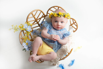 Ukrainian newborn baby girl dressed in elegant clothes in the colors of the Ukrainian flag. beautiful clothes and flowers on the head hair. Stylish clothes in trendy Ukraine colors