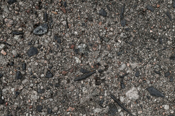 Close-up view of gray asphalt surface with colorful stones.