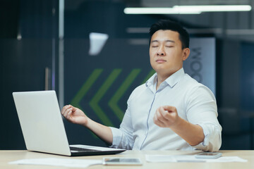 Portrait of Asian businessman, man in office working with laptop, meditating at workplace with eyes closed