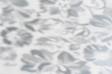 Obraz premium Gray blurred shadows of lace fabric with floral pattern as abstract background.