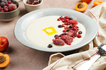 Traditional breakfast semolina porridge - creamy pudding with butter, frozen berries and fresh apricots in a grey plate
