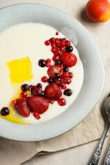 Traditional breakfast semolina porridge - creamy pudding with butter, frozen berries and fresh apricots in a grey plate