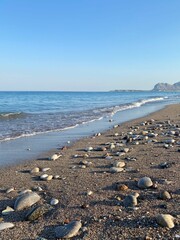 Pebble stones on the sea beach, the rolling waves of the sea with foam. Afandou (Afantou) beach, Rhodes island, Greece. 