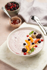 Traditional breakfast semolina porridge - purple creamy pudding with apricot slices, frozen berries, fresh mint, jelly on marble board
