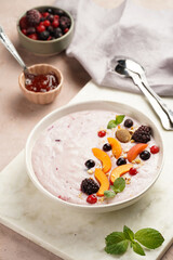 Traditional breakfast semolina porridge - purple creamy pudding with apricot slices, frozen berries, fresh mint, jelly on marble board