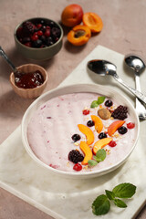 Traditional breakfast semolina porridge - purple creamy pudding with apricot slices, frozen berries, fresh mint, jelly on marble board
