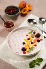 Traditional breakfast semolina porridge - purple creamy pudding with apricot slices, frozen berries, fresh mint, jelly on marble board